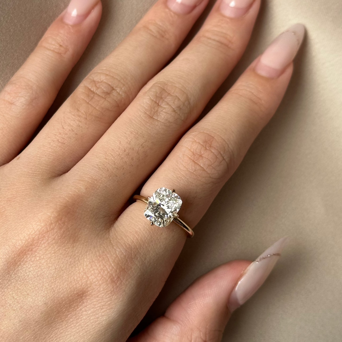 Cushion cut moissanite double claw solitaire engagement ring on a fine yellow gold band, view 2