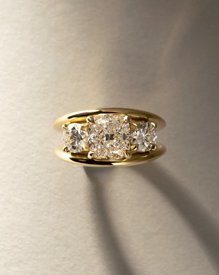Cushion cut moissanite three stone engagement ring on a double rail gold band in yellow gold