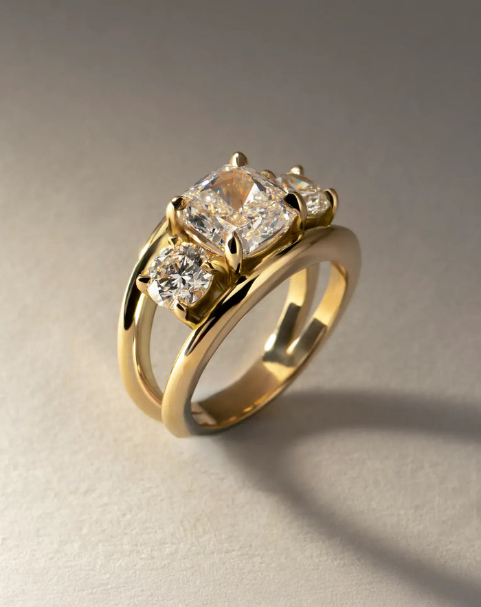 Cushion cut moissanite three stone engagement ring on a double rail gold band in yellow gold, view 2