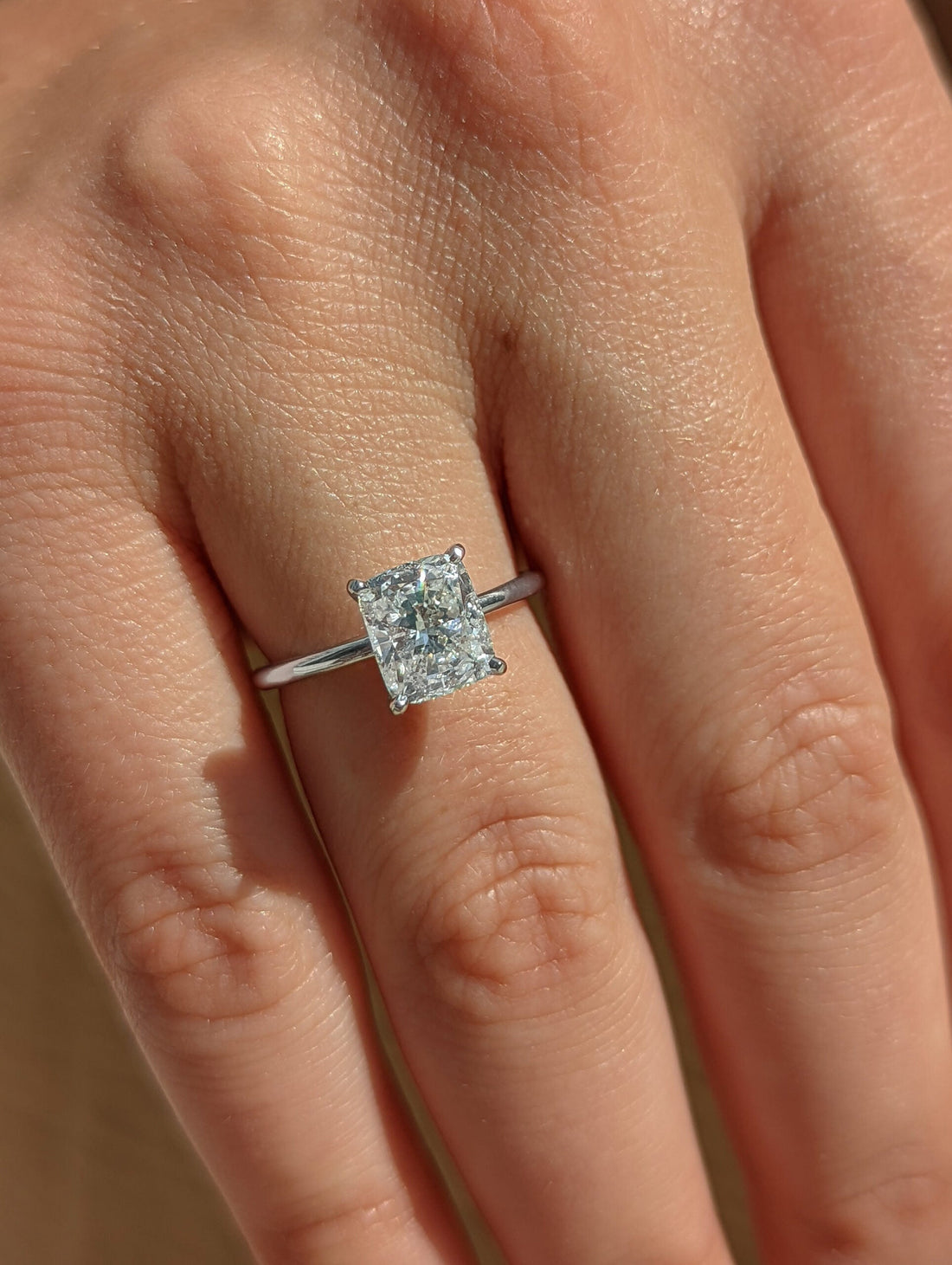 Cushion cut moissanite four claw solitaire engagement ring on a fine white gold band, view 2