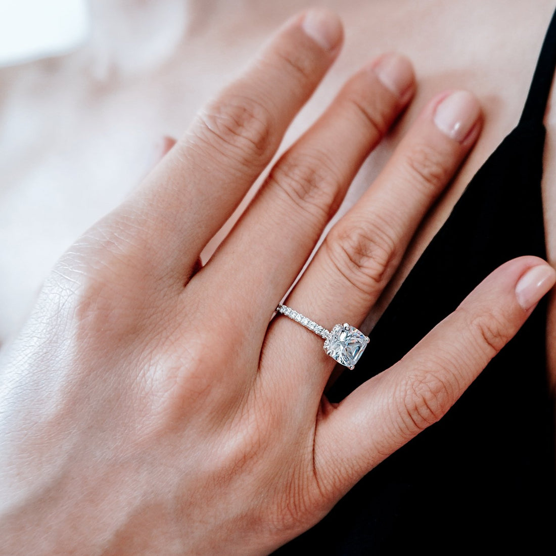 Cushion cut moissanite hidden halo engagement ring on a fine pave band in white gold
