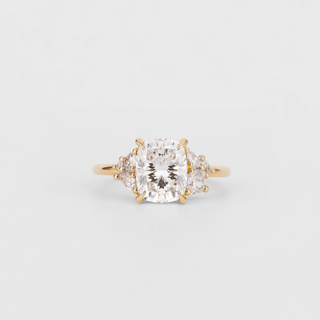 Cushion cut moissanite engagement ring with pear cluster shoulders in yellow gold