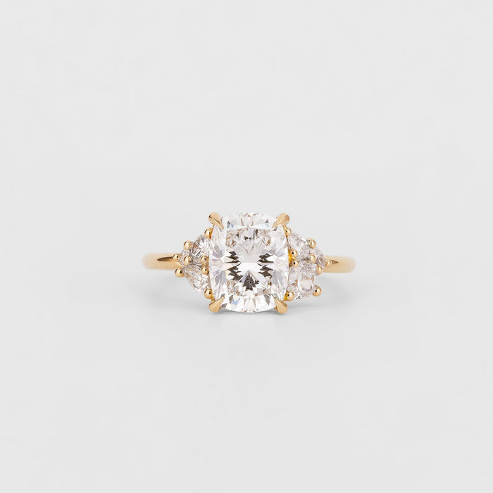 Cushion cut moissanite engagement ring with pear cluster shoulders in yellow gold