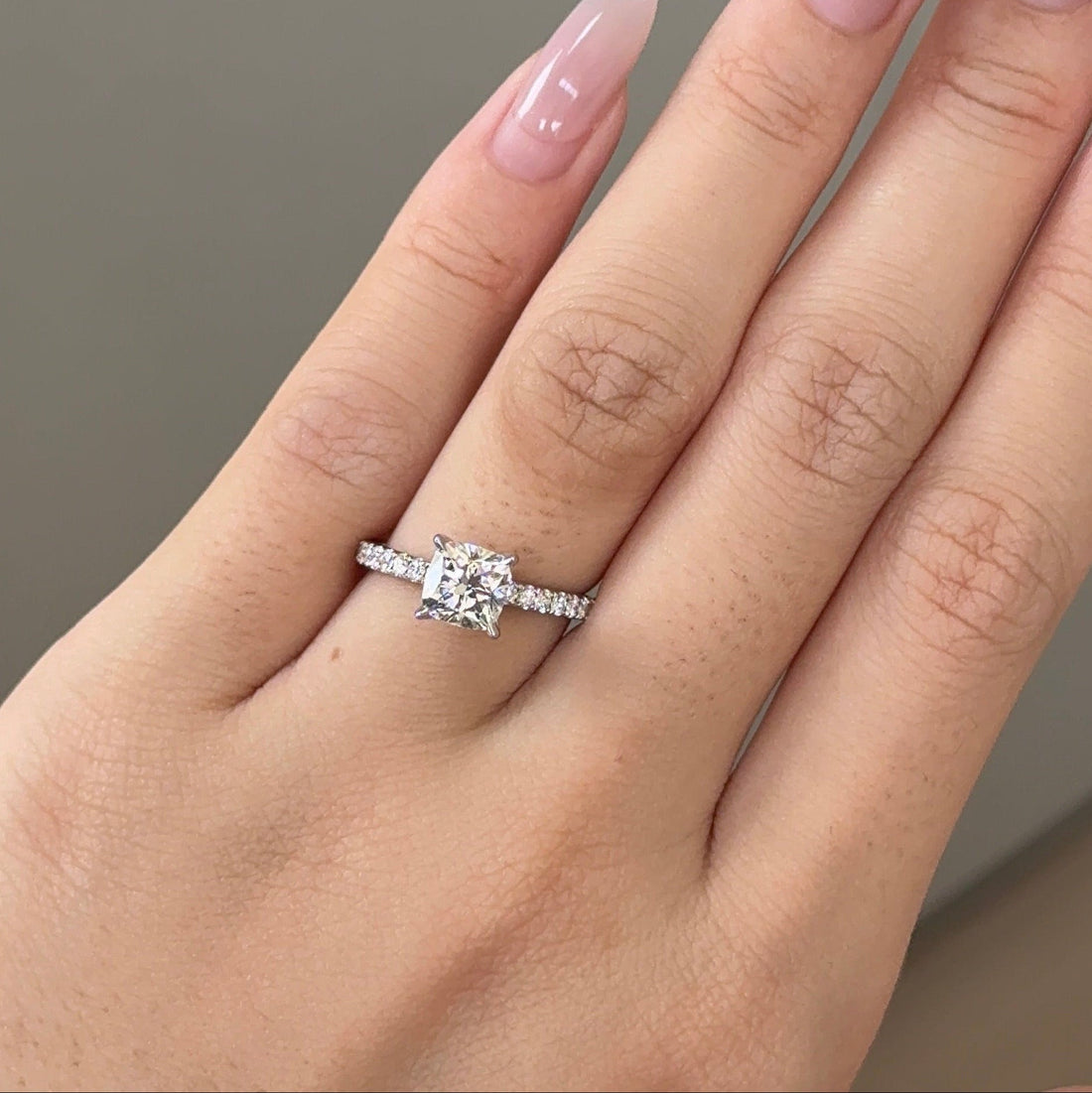 Cushion cut moissanite hidden halo engagement ring on a pave set white gold band