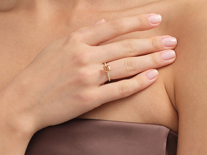 Cushion four claw pave band ring setting in yellow gold on the hand at the collarbone, yellow display stone