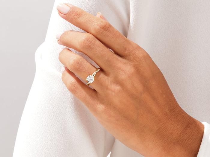 Cushion lab grown diamond braided engagement ring in yellow gold worn on the hand at the shoulder