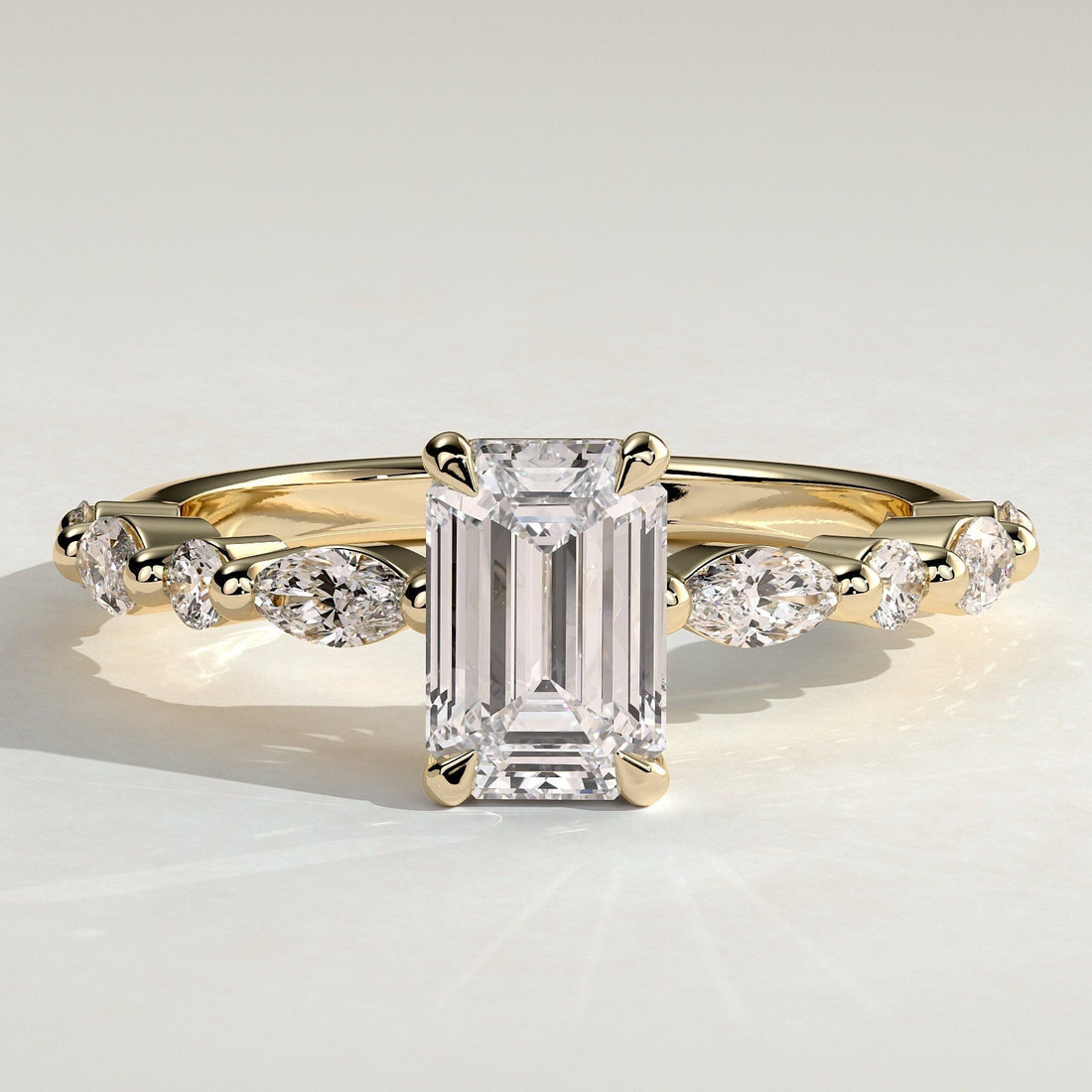 Emerald cut moissanite engagement ring with alternating marquise and round accents in yellow gold