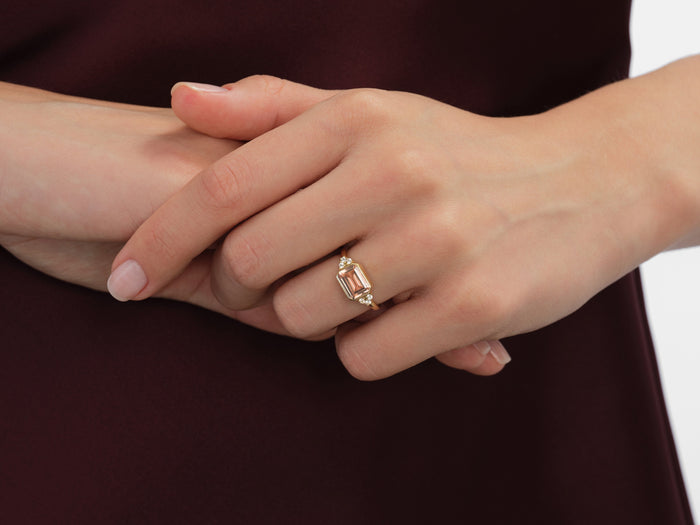East west emerald moissanite bezel ring in yellow gold worn on the hand, fingers clasped