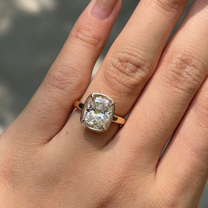 Elongated cushion moissanite bezel set engagement ring on a flat rose gold band