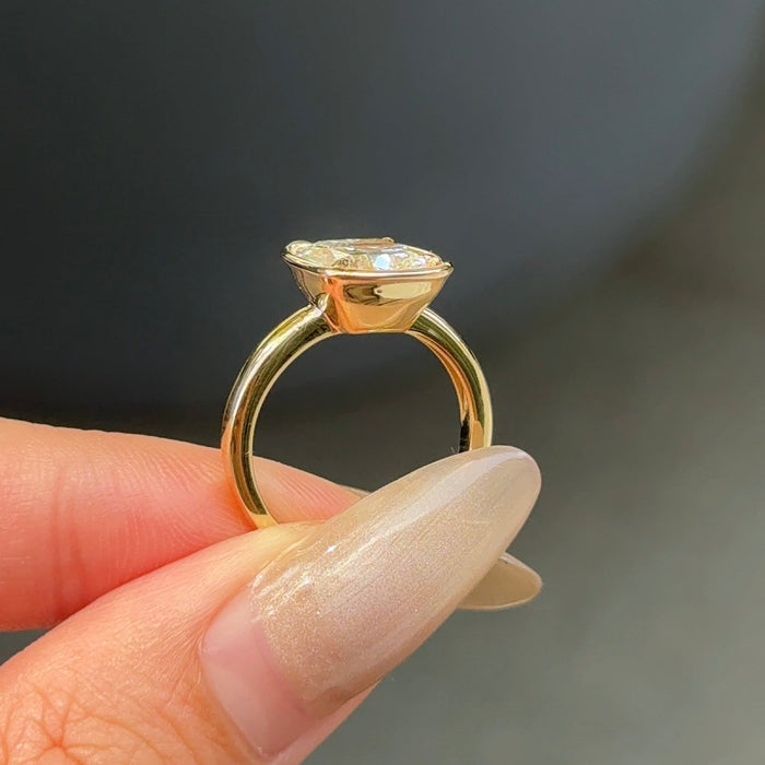 Elongated cushion moissanite bezel set engagement ring on a flat rose gold band, view 2