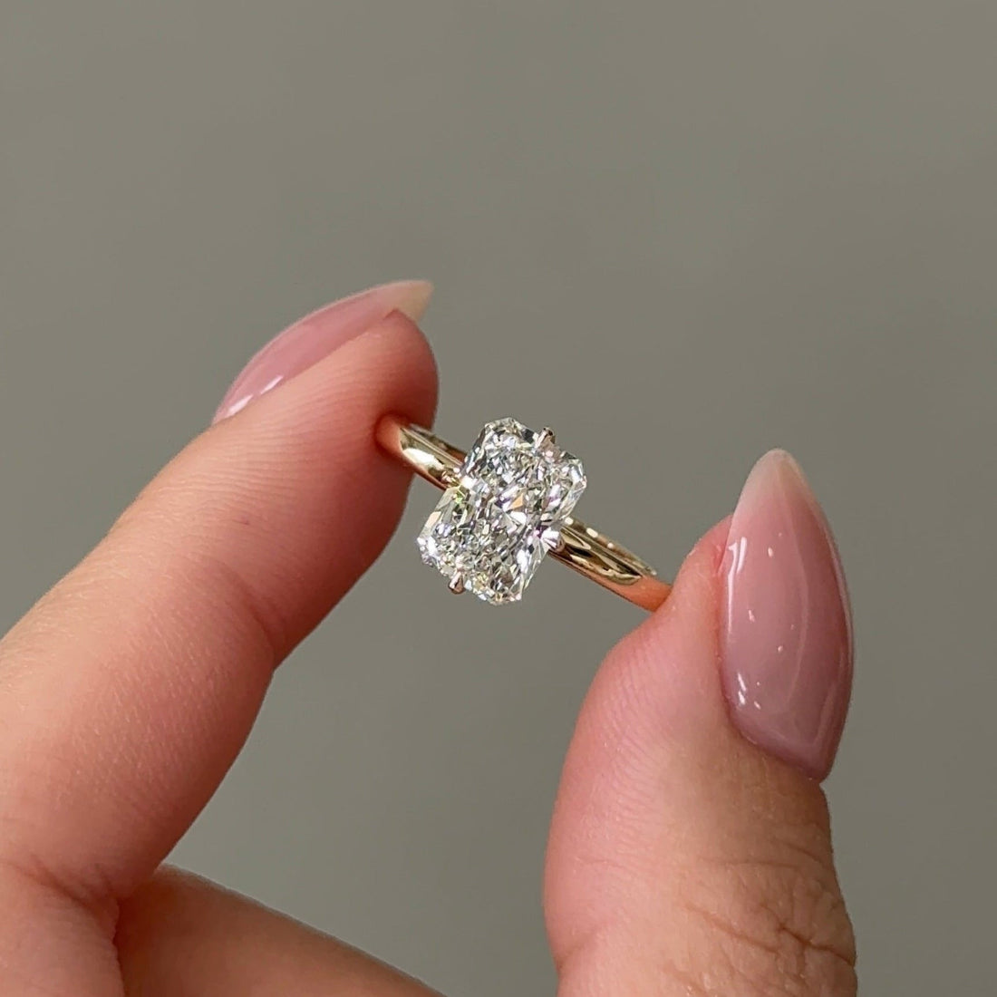Elongated cushion moissanite hidden halo engagement ring on a very fine yellow gold band