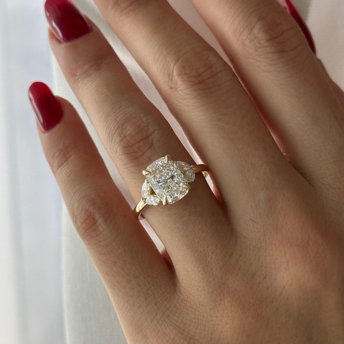 Elongated cushion moissanite three stone engagement ring with marquise side stones in yellow gold
