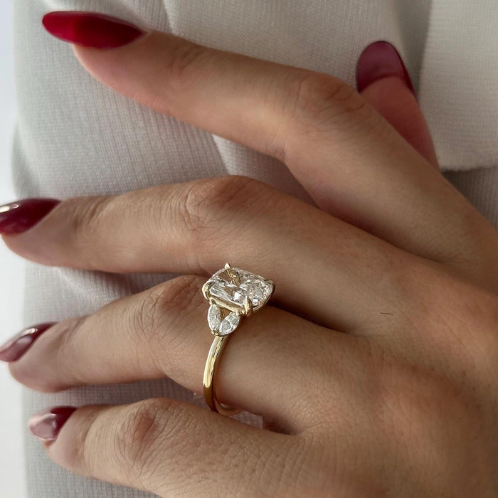Elongated cushion moissanite three stone engagement ring with marquise side stones in yellow gold, view 2