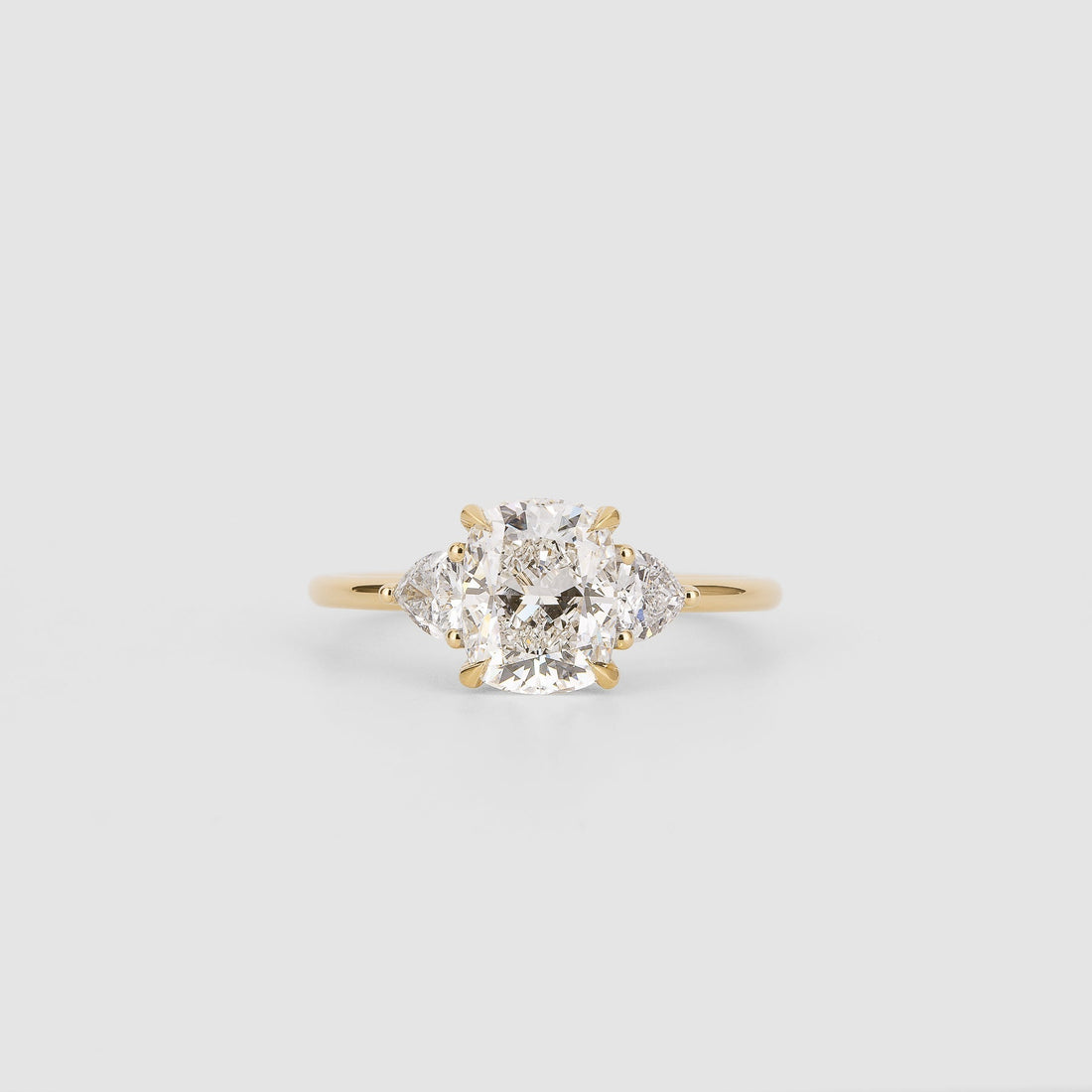 Elongated cushion moissanite three stone engagement ring with trillion side stones in yellow gold