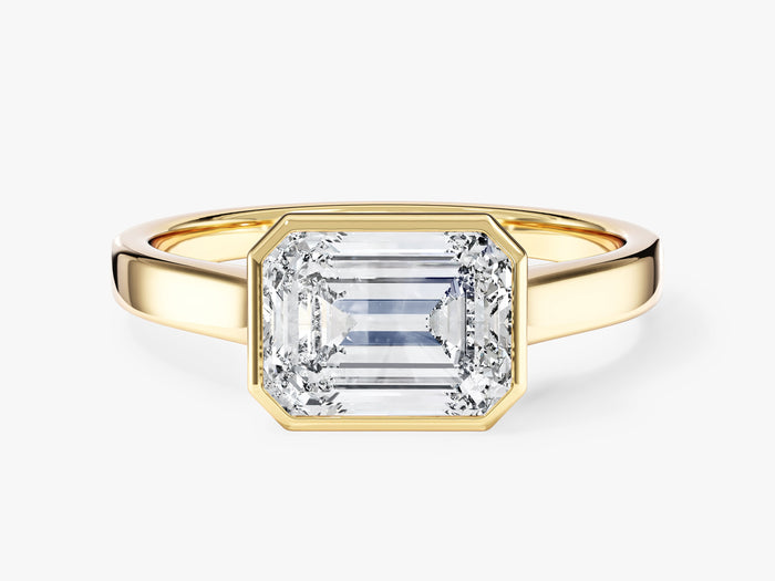 Emerald cut lab grown diamond east west bezel engagement ring on a flat band in yellow gold, front view
