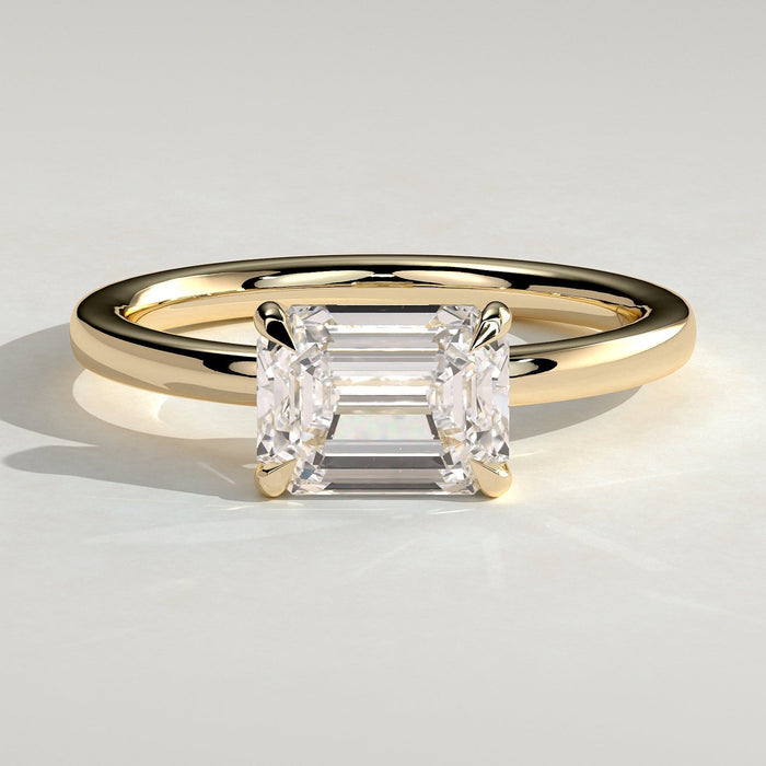 East west emerald cut moissanite solitaire engagement ring on a plain yellow gold band