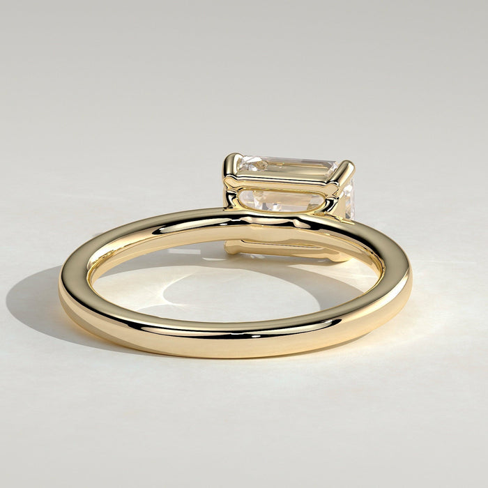 East west emerald cut moissanite solitaire engagement ring on a plain yellow gold band, view 2