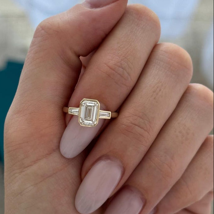 Emerald cut moissanite fine bezel engagement ring with tapered baguettes in yellow gold, view 2