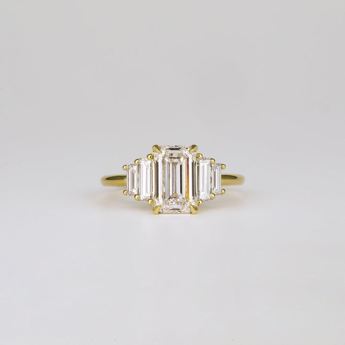 Emerald cut moissanite five stone engagement ring with graduated baguettes in yellow gold