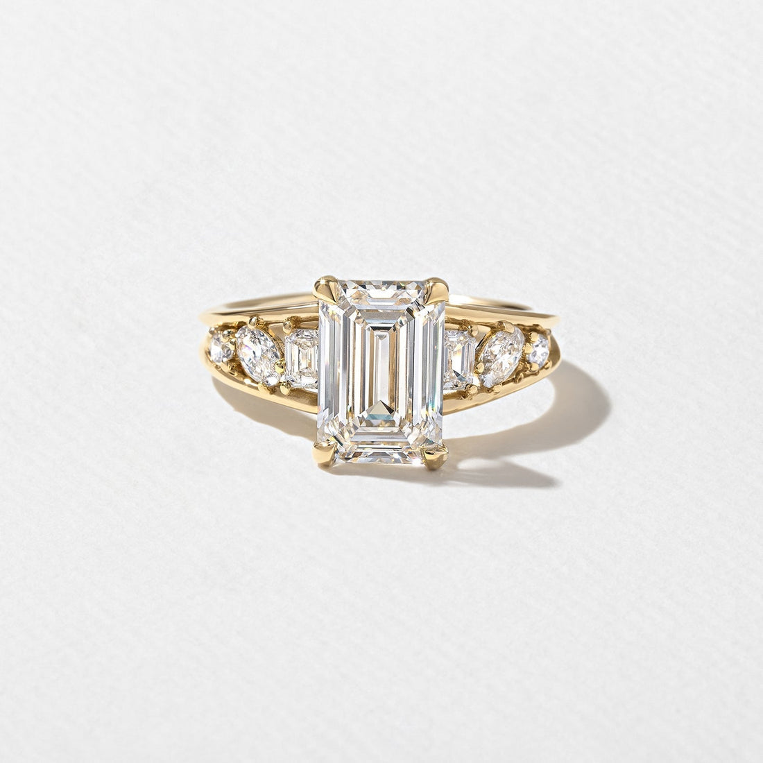Emerald cut moissanite engagement ring with graduated mixed cut shoulders in yellow gold