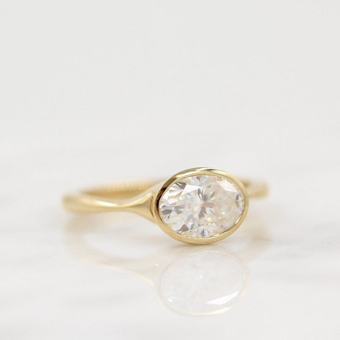 East west oval cut moissanite heavy rim bezel engagement ring in yellow gold, view 2