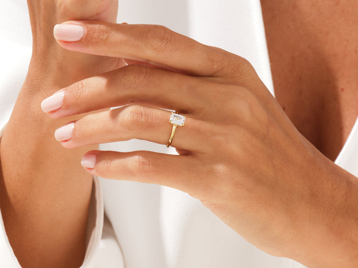 Emerald cut lab grown diamond minimalist solitaire on a hand held near the collar