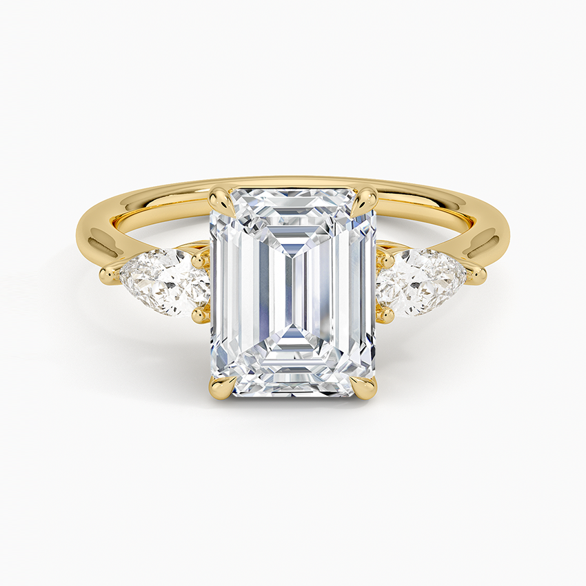 Emerald cut moissanite three stone ring with pear side stones in yellow gold, top view