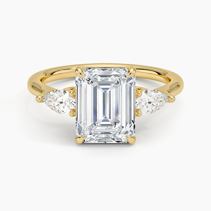 Emerald cut moissanite three stone ring with pear side stones in yellow gold, top view