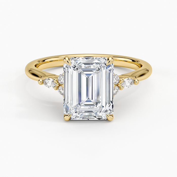 Emerald cut moissanite engagement ring with petite trio accent shoulders in yellow gold, top view