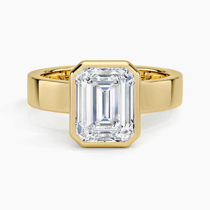Full bezel emerald cut moissanite engagement ring on a wide flat yellow gold band, top view