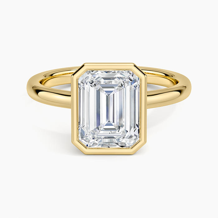 Emerald cut moissanite floating bezel ring on a slim round yellow gold band, top view