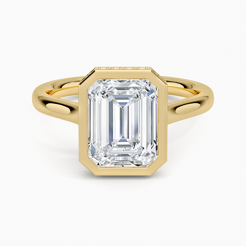 Emerald cut moissanite in a plain full bezel on an open split shank in yellow gold, top view