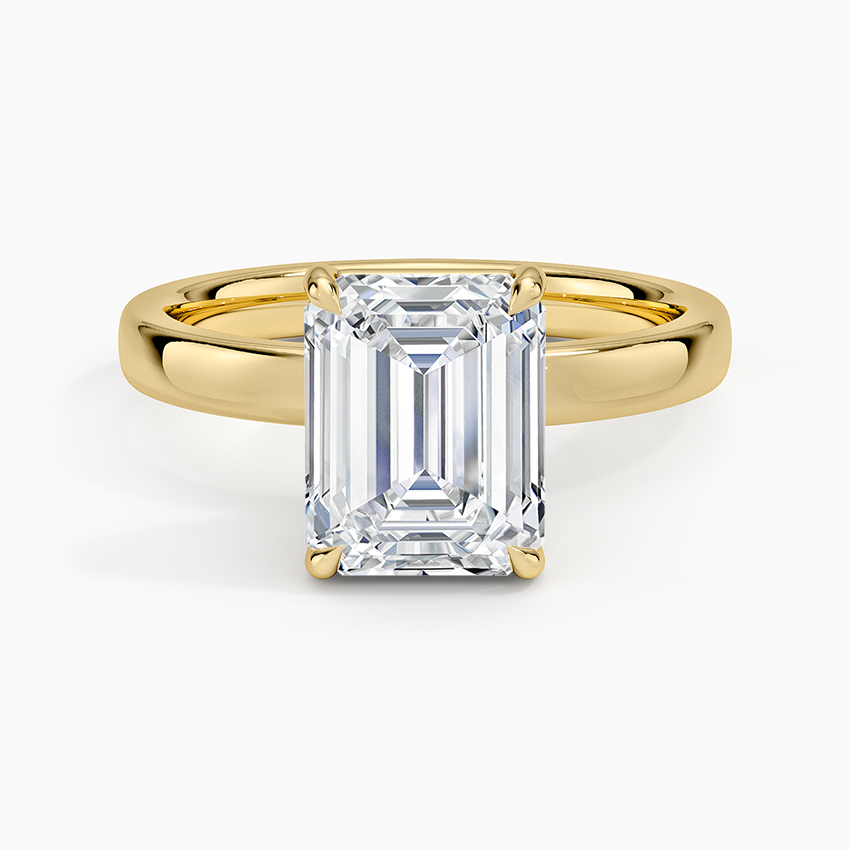 Emerald cut moissanite four claw solitaire on a plain band in yellow gold, top view