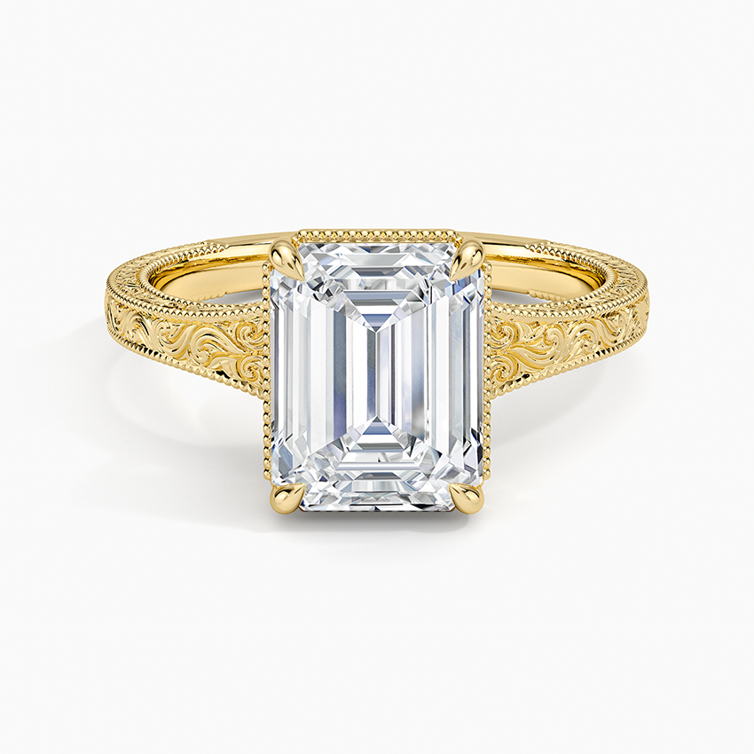 Emerald cut moissanite in a milgrain bezel on a hand engraved scroll band in yellow gold, top view