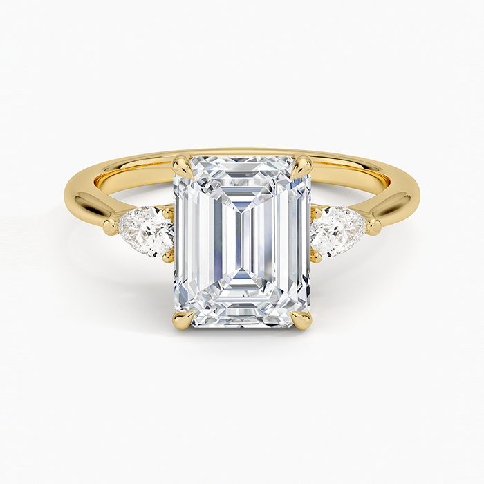 Emerald cut moissanite with pear cut side stones in yellow gold, top view