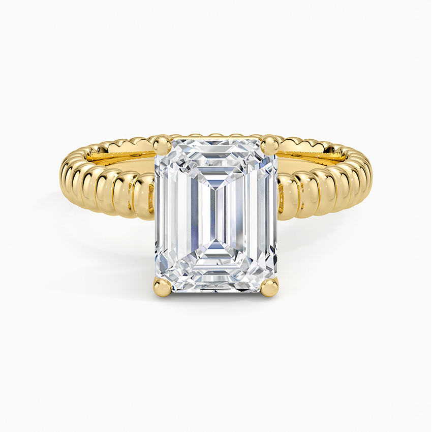 Emerald cut moissanite solitaire on a ribbed croissant dome band in yellow gold, top view