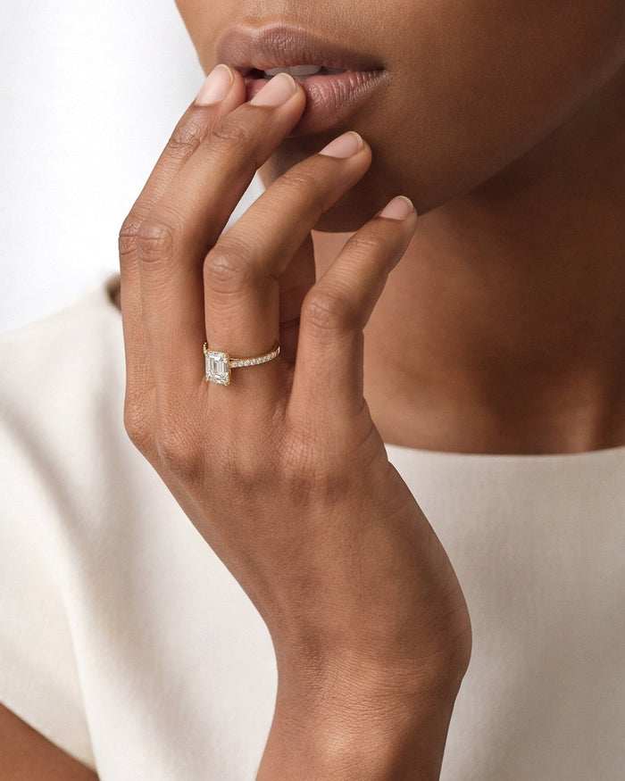 Emerald lab grown diamond micro pave ring in yellow gold worn on the hand at the lips
