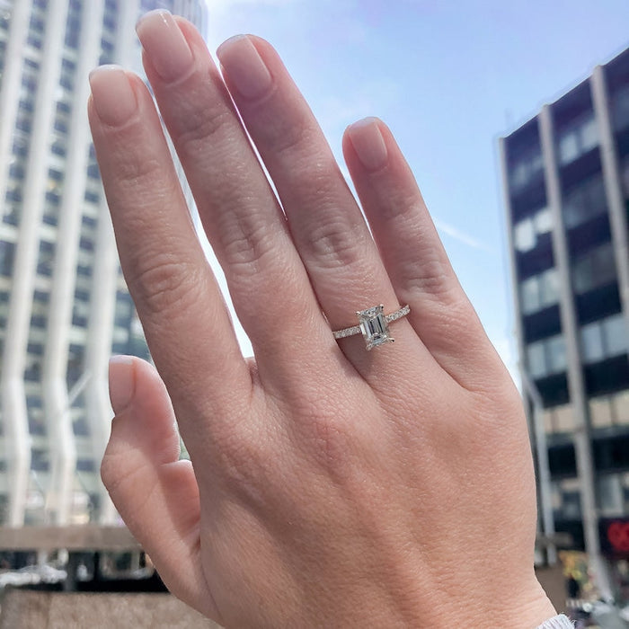 Emerald cut moissanite solitaire engagement ring on a fine pave white gold band