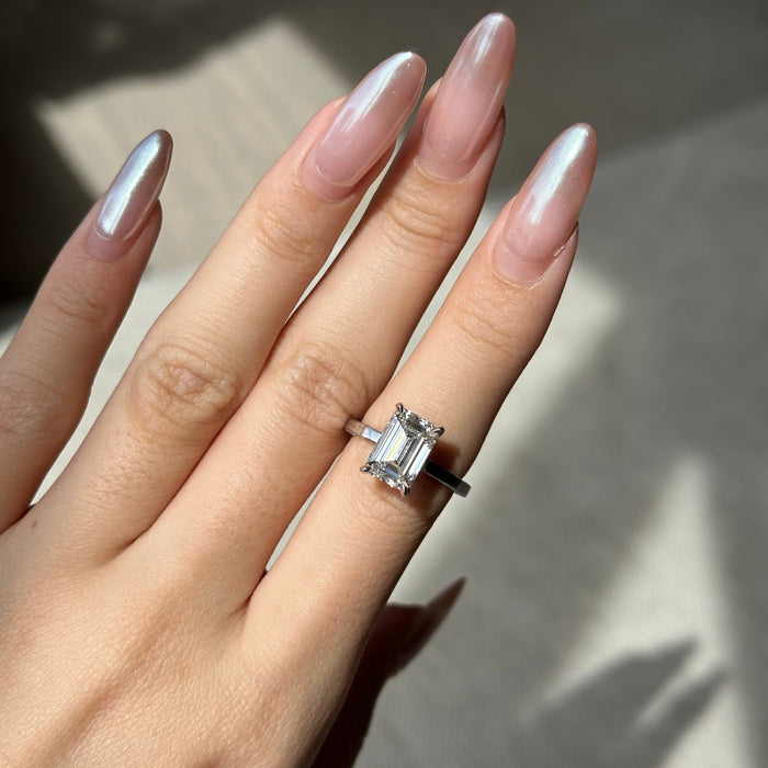 Emerald cut moissanite hidden halo engagement ring on a fully paved white gold shank
