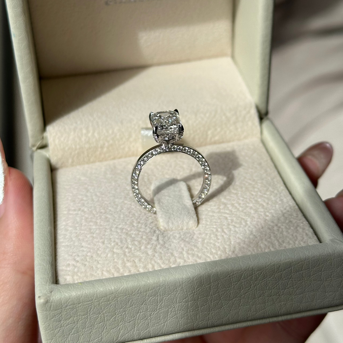Emerald cut moissanite hidden halo engagement ring on a fully paved white gold shank, view 2