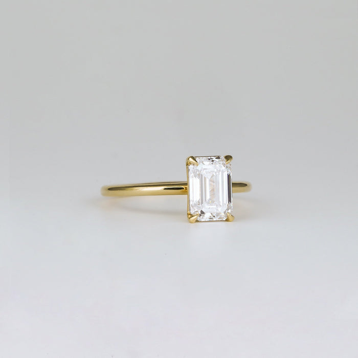 Emerald cut moissanite petite four claw solitaire engagement ring on a fine yellow gold band, view 2