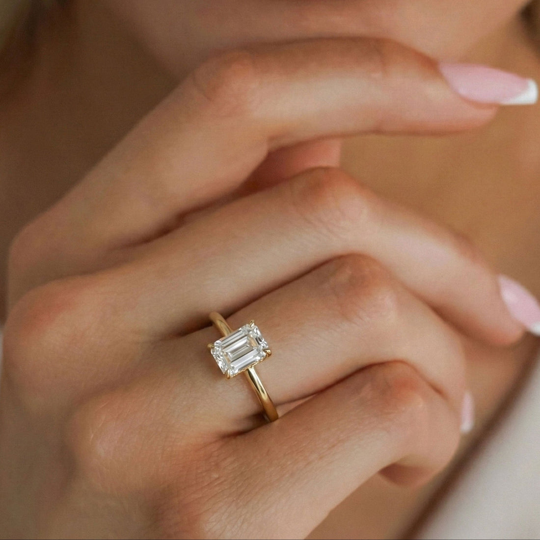 Emerald cut moissanite solitaire engagement ring with a rounded band in yellow gold