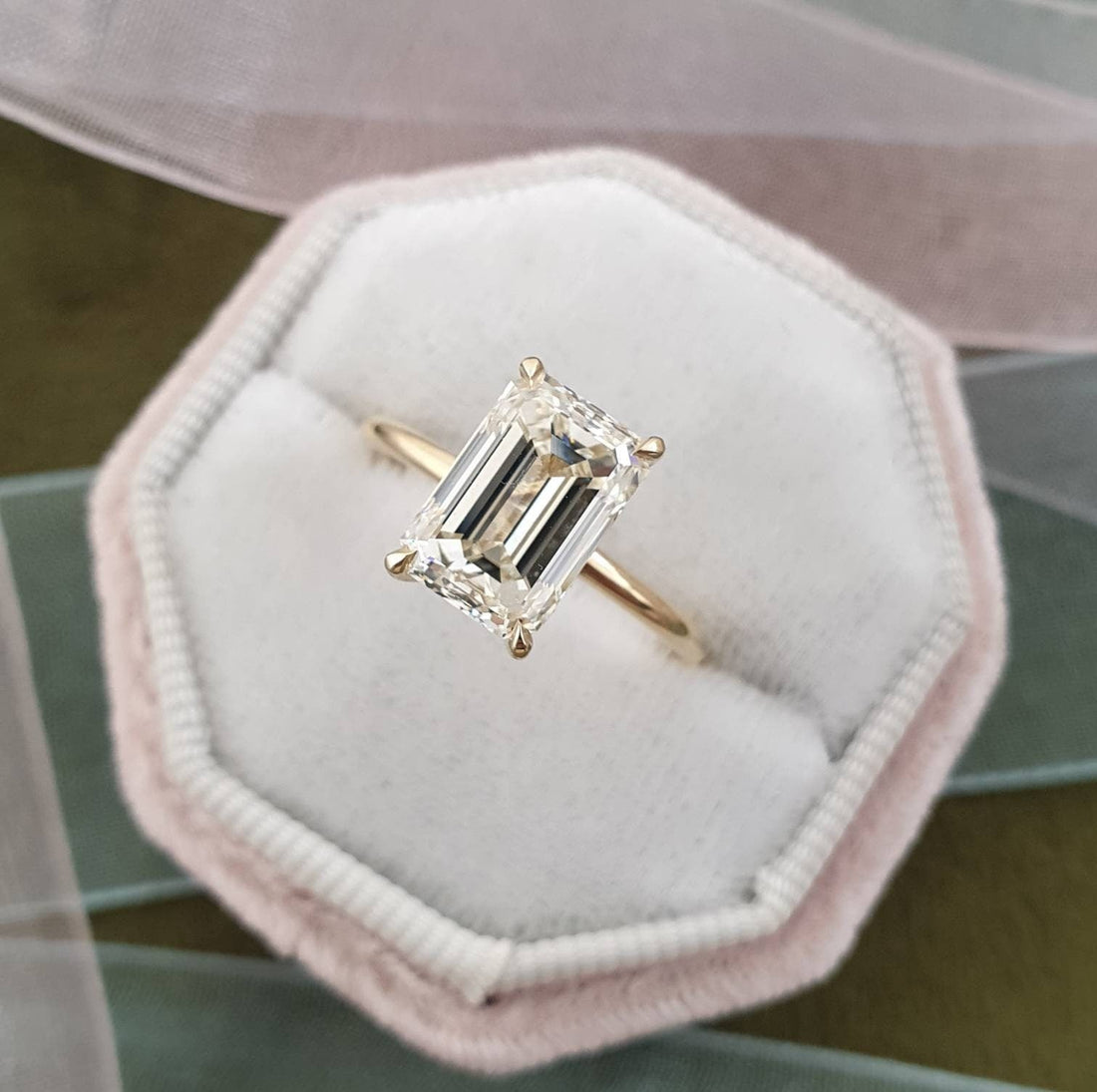 Emerald cut moissanite solitaire engagement ring on a round wire hairline yellow gold band