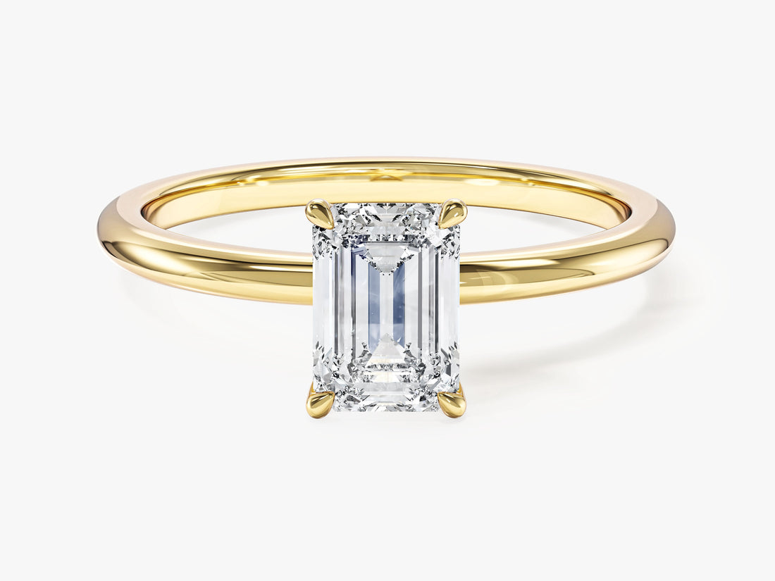 Dainty emerald cut moissanite solitaire engagement ring on a thin yellow gold band, front view