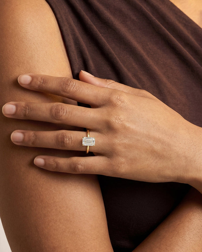 Emerald cut lab grown diamond statement solitaire in yellow gold worn on the hand across the arm