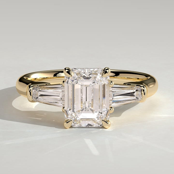 Emerald cut moissanite three stone engagement ring with tapered baguette sides in yellow gold