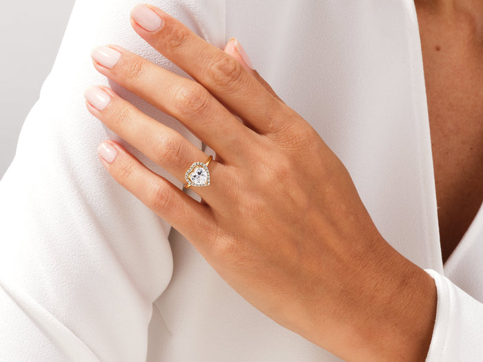 Heart shaped moissanite halo ring in yellow gold worn on the hand