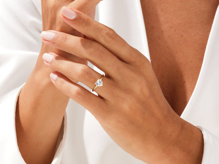 Heart cut lab grown diamond dainty solitaire in yellow gold worn on a hand with fingers crossed