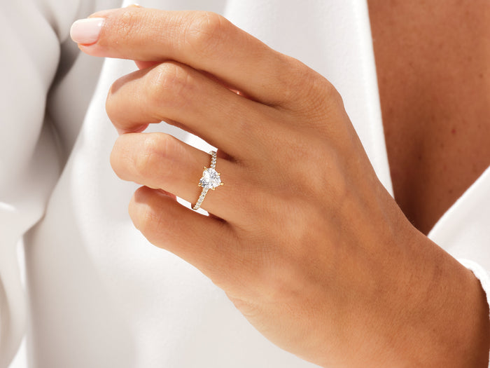 Heart cut lab grown diamond solitaire in rose gold on a hand held near the collar