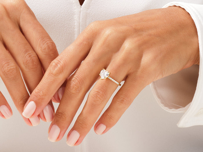 Heart moissanite accented solitaire ring in rose gold worn on the hand
